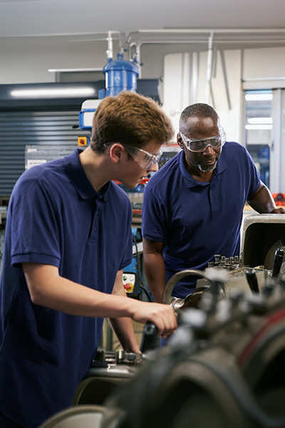 Mechanist showing a student how to use a lathe